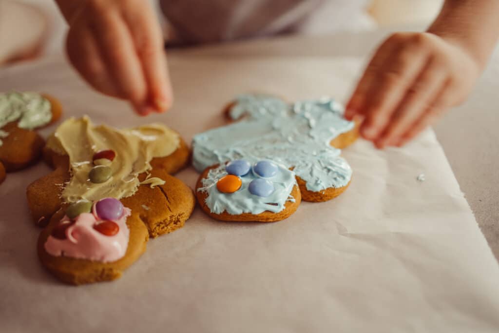Foster care child decorating gingerbread cookies with colorful icing and candies, showing creativity and holiday joy.